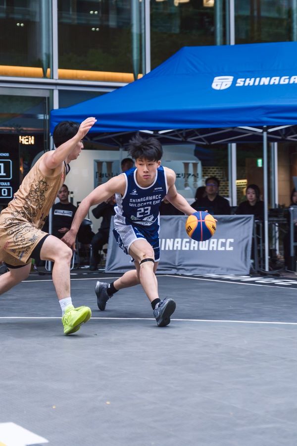 商業施設前の特設コートで行われる3x3の試合。ドリブルで攻め込む選手とディフェンス